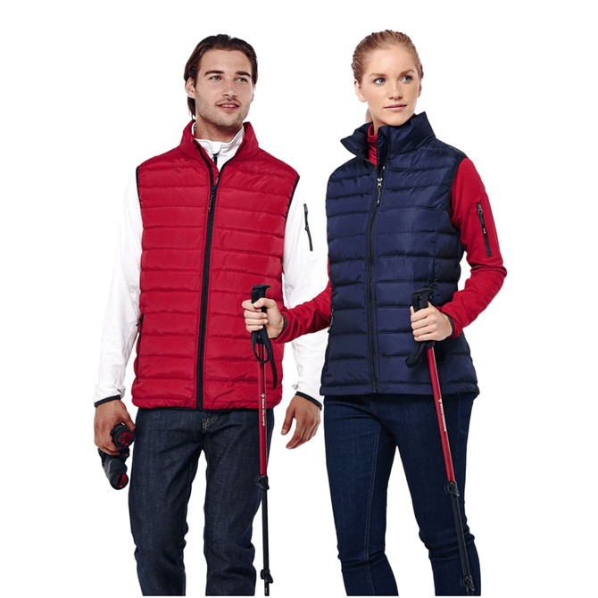 A red and navy insulated vest worn by a man and a woman, both holding trekking poles and wearing casual clothing.