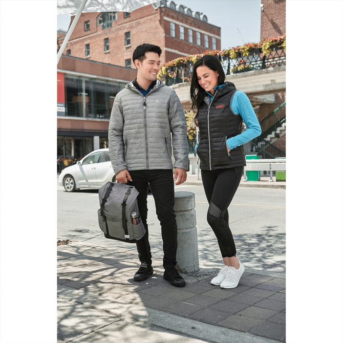 A pair of models wearing a grey puffer jacket and a black insulated vest, set in an urban environment.