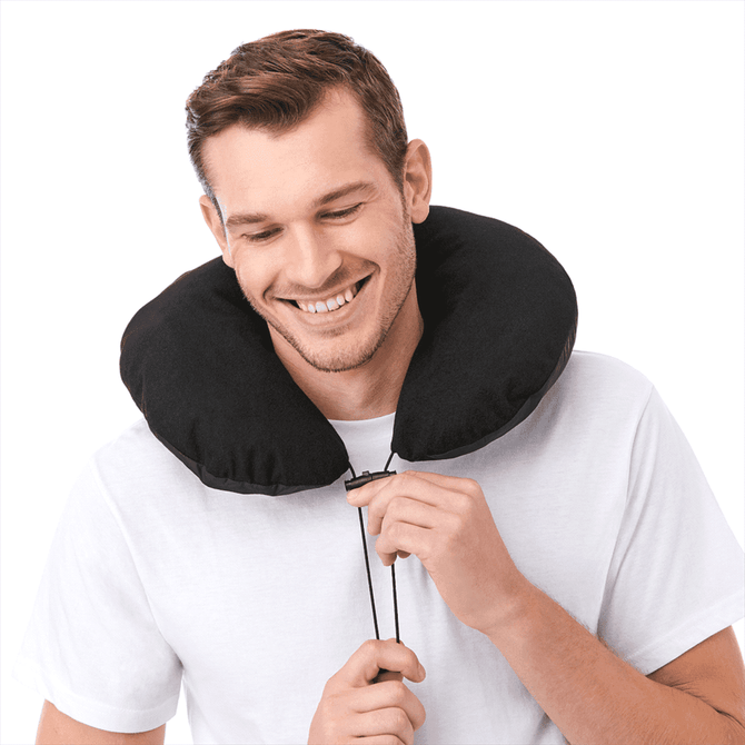 A man smiles while wearing a black travel neck pillow with a drawstring, showcasing its comfortable design.