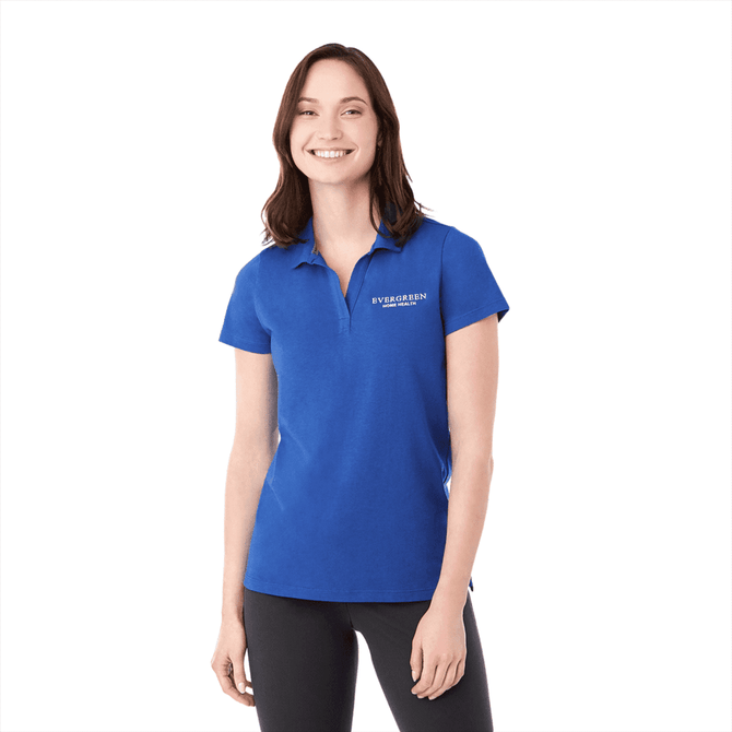 A woman wearing a blue short sleeve polo shirt with a logo. The top has a classic collar and a fitted design.
