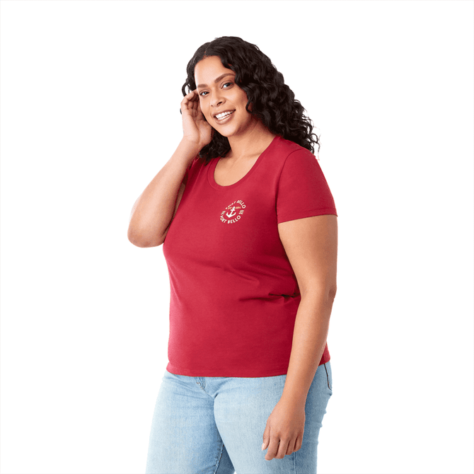 A red short sleeve women's tee featuring a logo on the front, styled with blue jeans and curly hair.