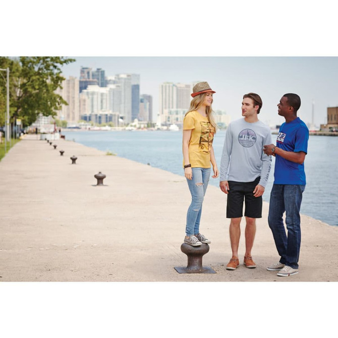 A group of three people by the water, wearing Omi short sleeve tech tees in grey, yellow, and blue. 