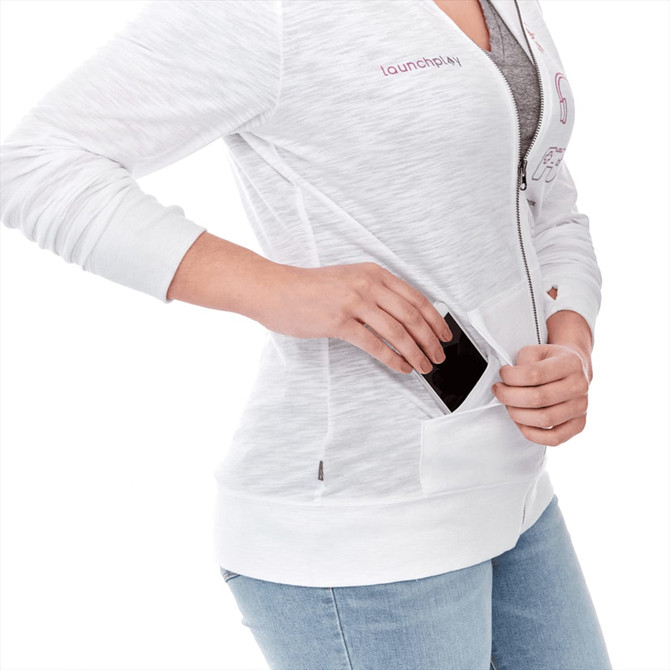 A white women's hoodie with a full zip, featuring a pocket and a logo, worn with light blue jeans.