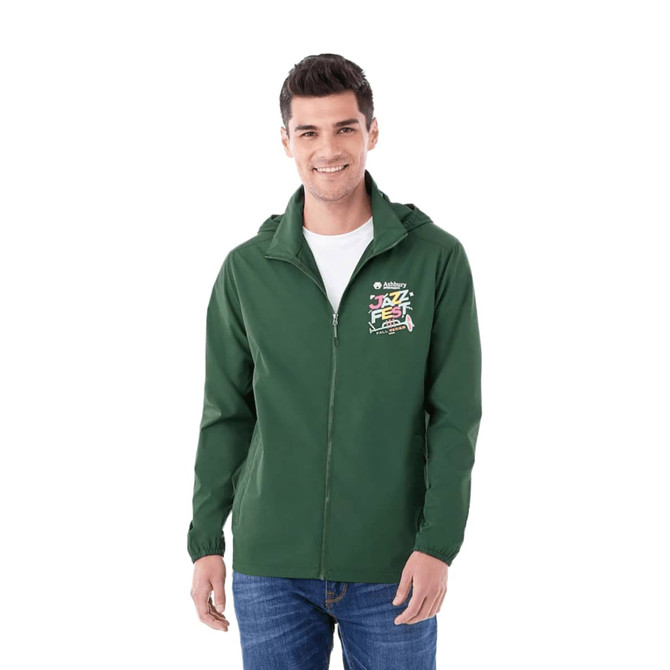 A man wearing a green packable rain jacket with a hood and a logo on the chest.
