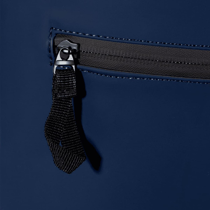 A navy blue roll-top backpack featuring a zippered pocket with a black pull tab and stitching details.