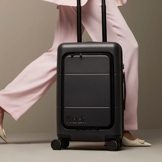 A black carry-on suitcase with wheels and a retractable handle, featuring branding on the front.