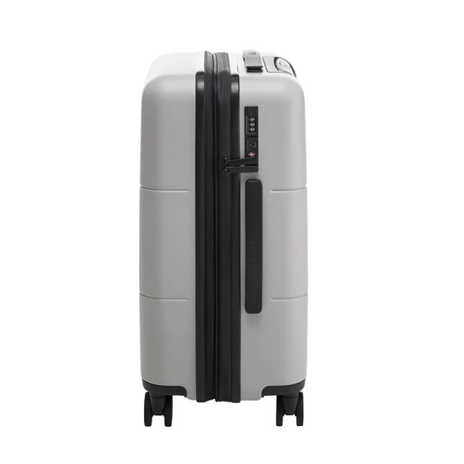A grey carry-on suitcase with a smooth finish, featuring black accents and wheels for mobility.