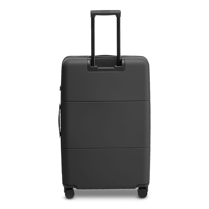 A large black suitcase with a retractable handle and wheels, featuring a smooth surface and an attached logo.
