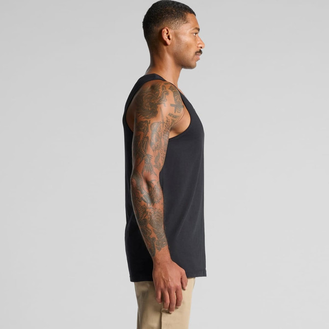 A sleeveless black singlet worn by a man, showcasing a side view and intricate arm tattoos. The singlet has a logo.