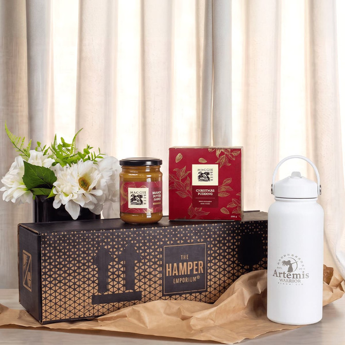 A white drink bottle, a jar of jam, a box of tea, and a floral arrangement in a gift box.