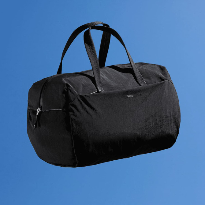 A black duffle bag with two handles and a branded logo, set against a blue background.