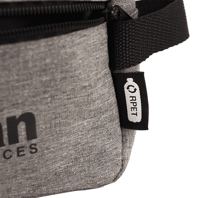A grey bag with a zipper and a strap, featuring a small tag. The bag has a simple, modern design.