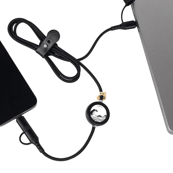 A black charging cable with a circular connector, linking a device to a laptop, featuring a logo.