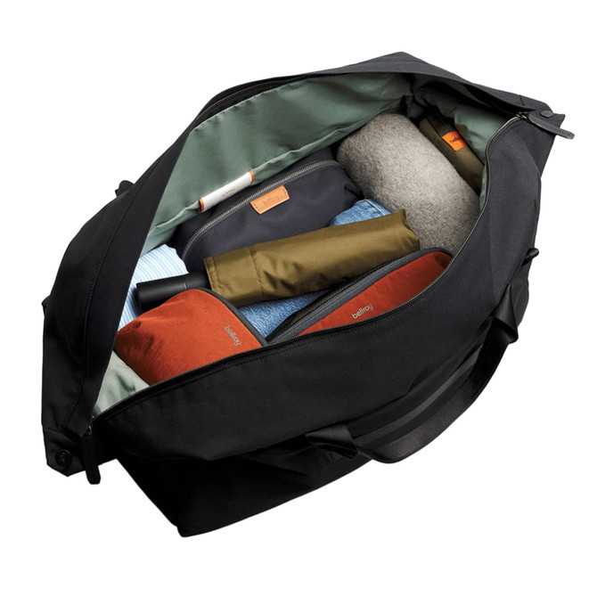 A black duffel bag open to reveal neatly packed items, including clothing and accessories in various colours.