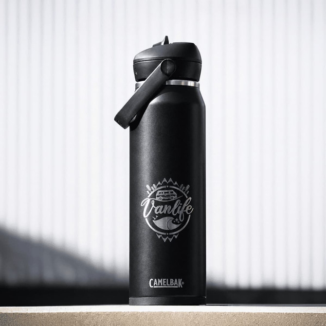 A drink bottle in matte black with a flip straw lid and a logo featuring a vanlife theme.