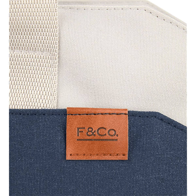 A navy and cream tote bag featuring a leather tag with branding and sturdy woven straps.
