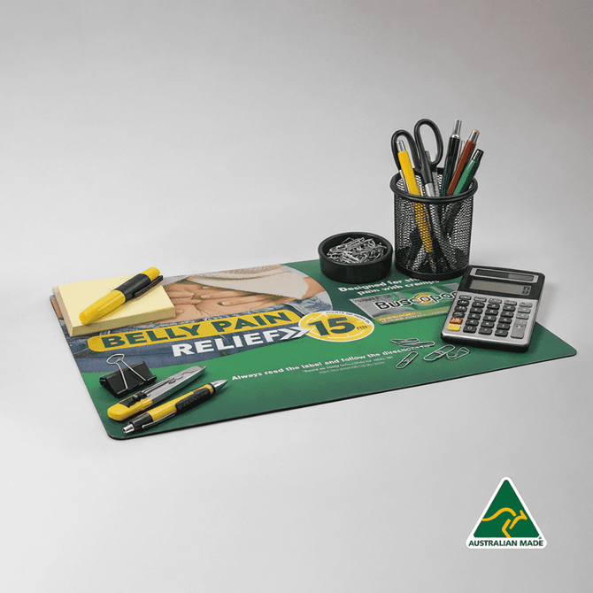 A green counter mat featuring a graphic design, surrounded by stationery including pens, a calculator, and a pencil holder.