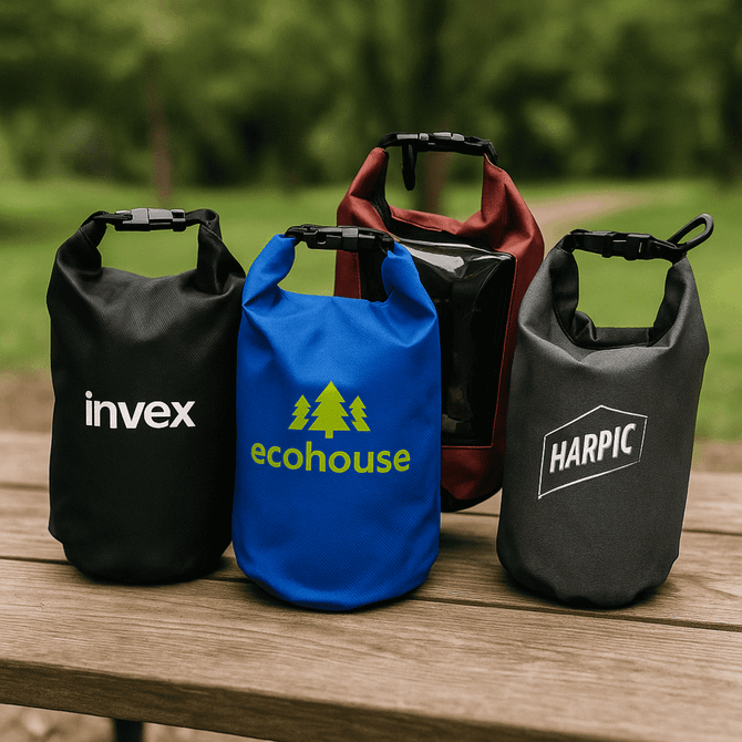 Four dry bags in various colours: black, blue, red, and grey, each featuring branding on the front.