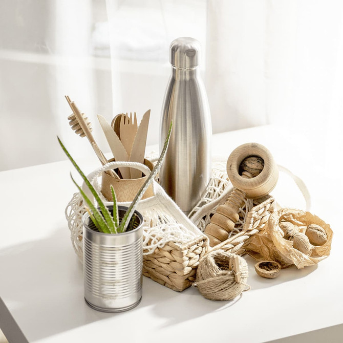 A drink bottle made of stainless steel, featuring a sleek design, placed among natural materials in a basket.