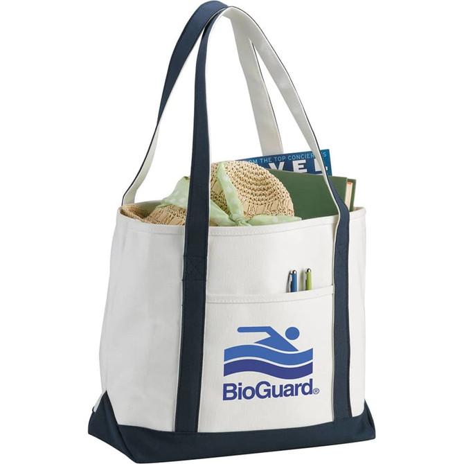 A cream and navy tote bag featuring a logo, filled with books, a towel, and a pen.