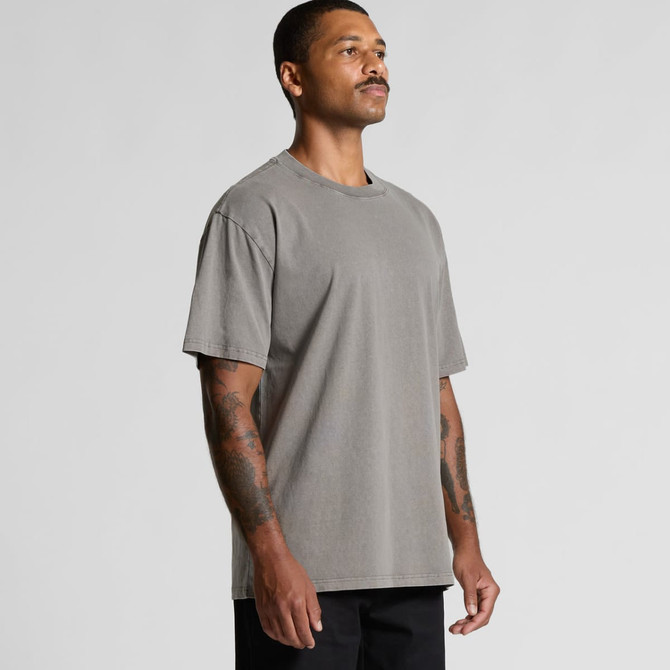 A man wearing a heavy faded grey T-shirt, displaying a relaxed fit and short sleeves. The shirt features a logo.