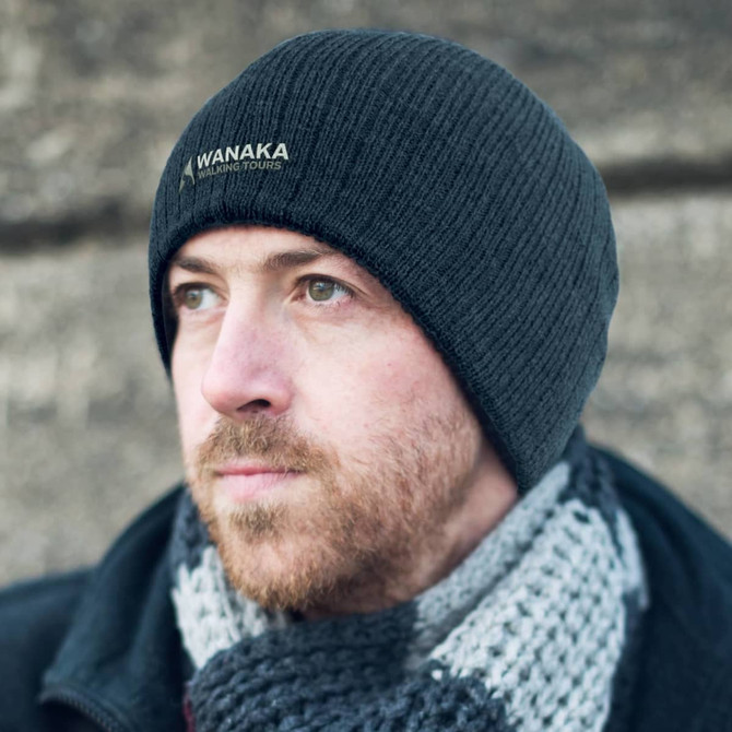 A Nebraska Cable Knit Beanie in black, featuring a subtle logo and a textured knit design.