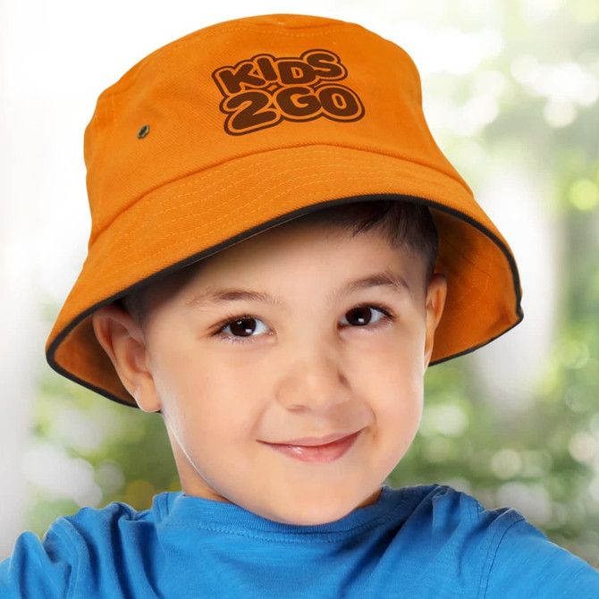 A bright orange bucket hat with a logo, worn by a smiling young child against a blurred background.