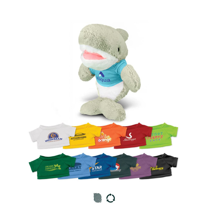 A soft, grey and white shark plush toy wearing a blue shirt, surrounded by various colourful t-shirts in different shades.