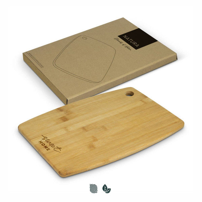 A bamboo chopping board in a rectangular shape with a hanging hole, placed on top of its packaging.