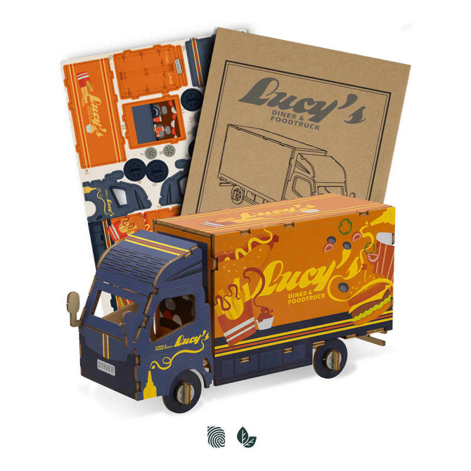 A wooden model of a small truck in blue and orange, with accompanying assembly materials and stickers.