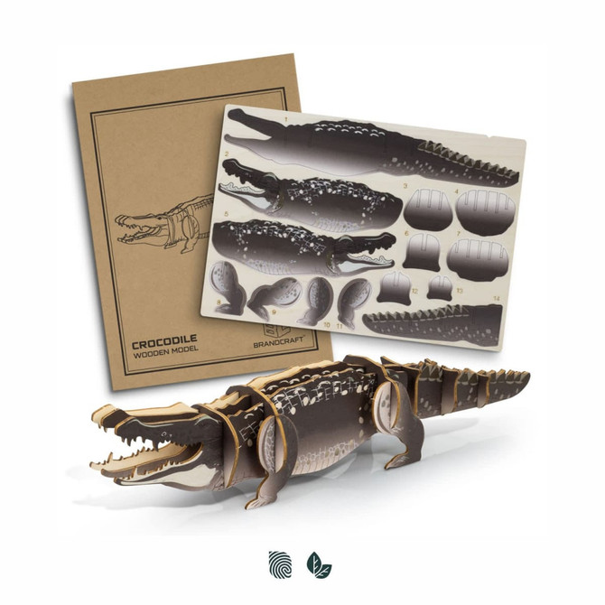 A wooden model of a crocodile in brown and beige, with assorted parts displayed on a cardboard backing, featuring a logo.