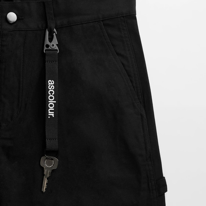 A black keychain features a clip and a metal key, attached to a sturdy strap with a logo.
