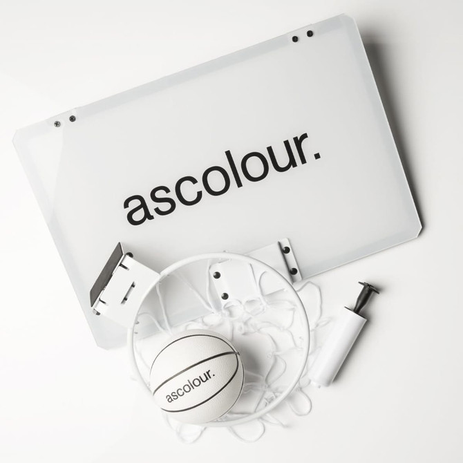 A mini basketball set featuring a white backboard, a basketball, a pump, and hardware for mounting, all with branding.