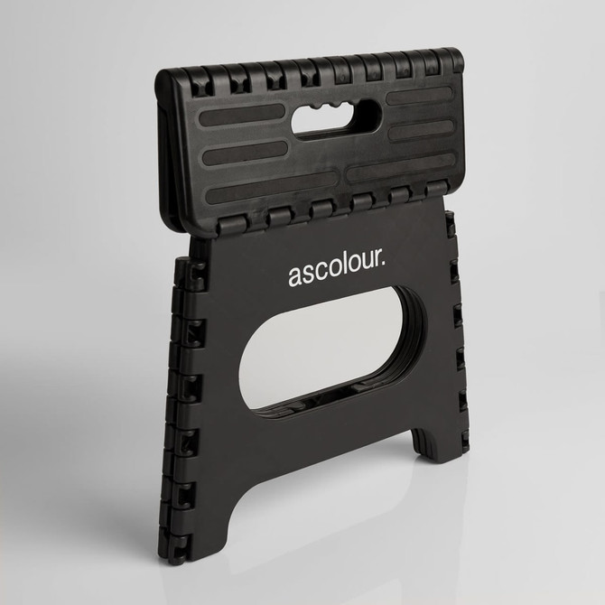 A black folding stool with a textured surface and a handle, featuring a logo on the front.