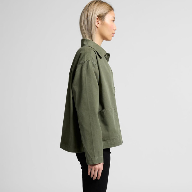A side view of a green chore jacket with a relaxed fit and a chest pocket. The model is wearing black pants.