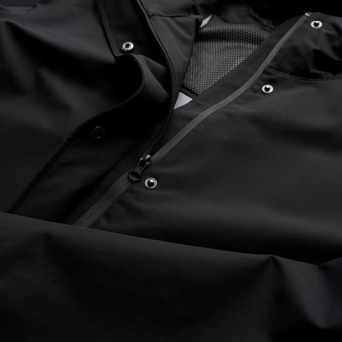 A soft shell jacket in black, featuring a zip and snap closures, with a textured interior lining.