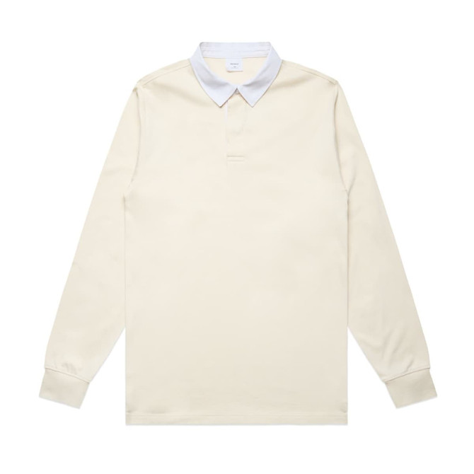 A rugby jersey featuring a cream body and light blue collar, with long sleeves and a logo present.