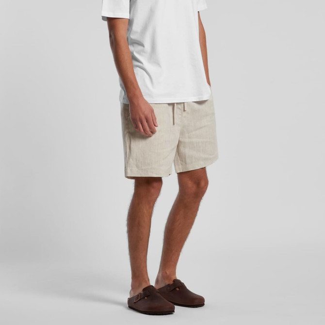 Linen shorts in a light beige colour, featuring an elastic waistband and a casual style. Worn with a plain white T-shirt.
