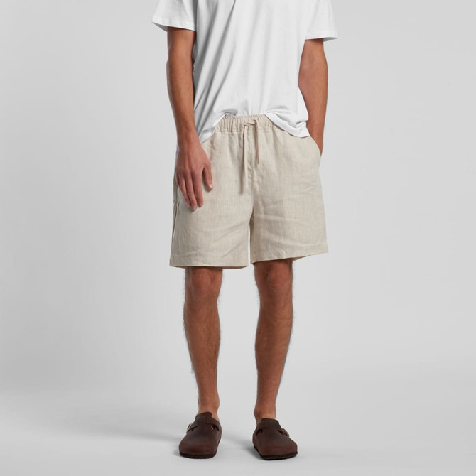 Linen shorts in a light beige colour, featuring an elastic waistband and side pockets, worn with a white t-shirt.