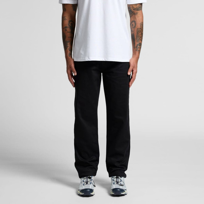 Relaxed black pants displayed on a person standing with hands by their sides, wearing a white t-shirt and sneakers.
