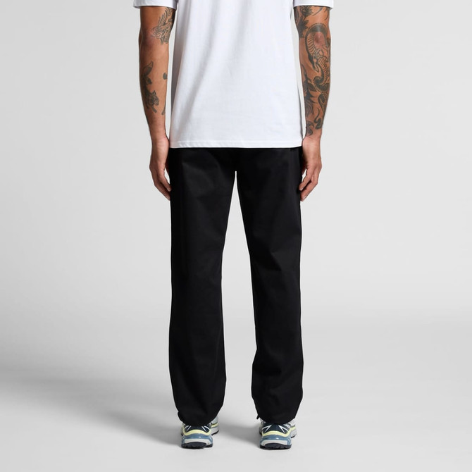 Relaxed pants in black featuring a relaxed fit, viewed from the back. The model wears a white shirt and sneakers.