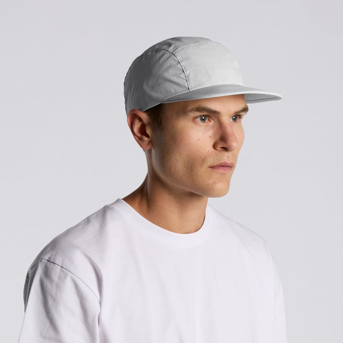 A grey nylon cap with a flat brim, worn by a model in a white t-shirt. The cap has a logo on it.