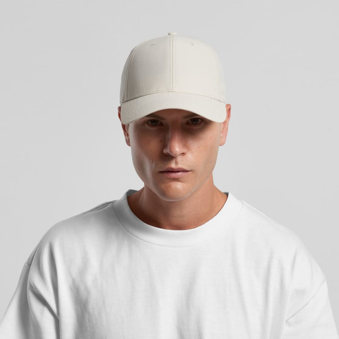 A light beige nylon cap displayed on a model wearing a white sweatshirt. The cap features a logo.