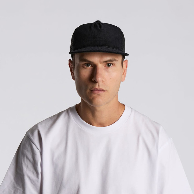 A black trucker cap featuring a mesh back, worn by a model dressed in a white T-shirt.