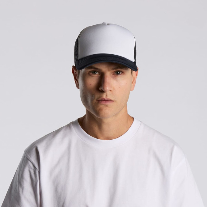A two-tone trucker cap in white and black, featuring a logo on the front, worn by a model in a white t-shirt.