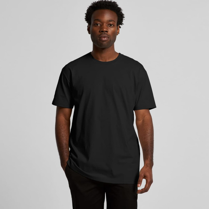A black t-shirt is worn by a model with short, curly hair, standing against a plain background.