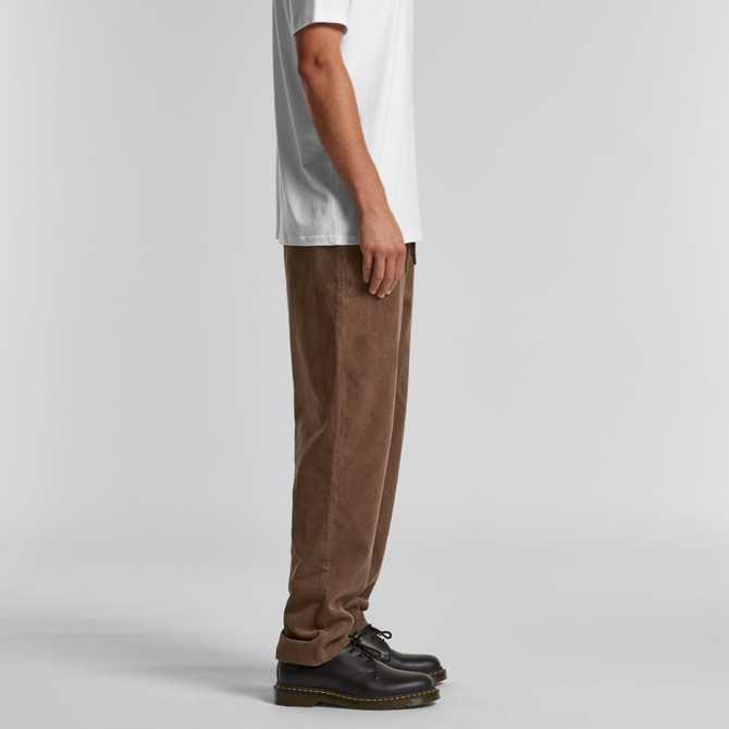 Cord pants in brown, displayed from the side on a model wearing a white T-shirt and black shoes.