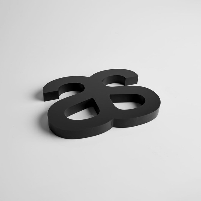 A black acrylic logo plaque with a distinctive design, suitable for awards and trophies.