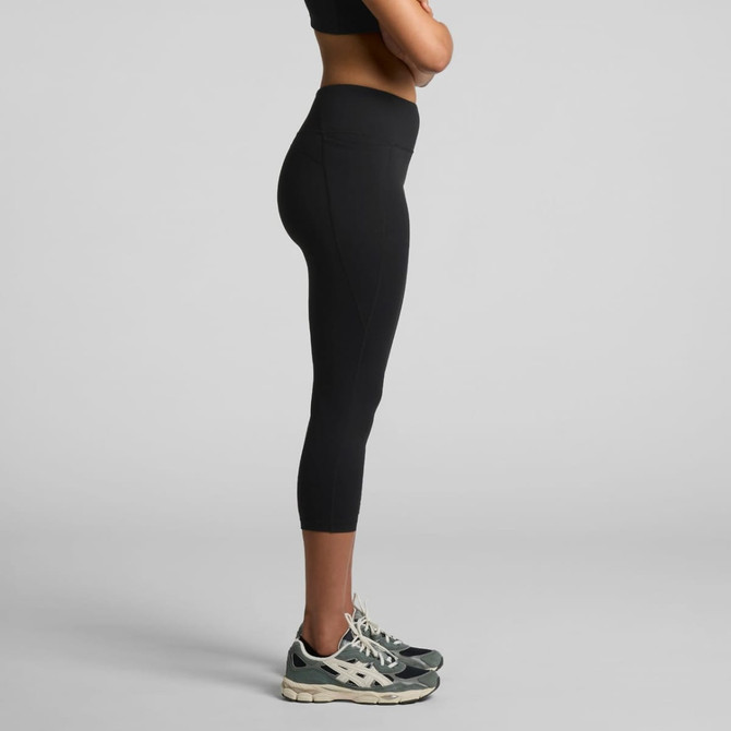 A pair of black mid-length leggings with a fitted design, paired with athletic shoes, displayed from the side.