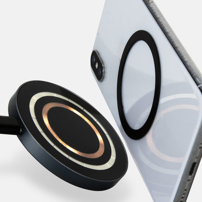A wireless charger in black and metallic gold, positioned next to a smartphone with a matching circular design on its back.